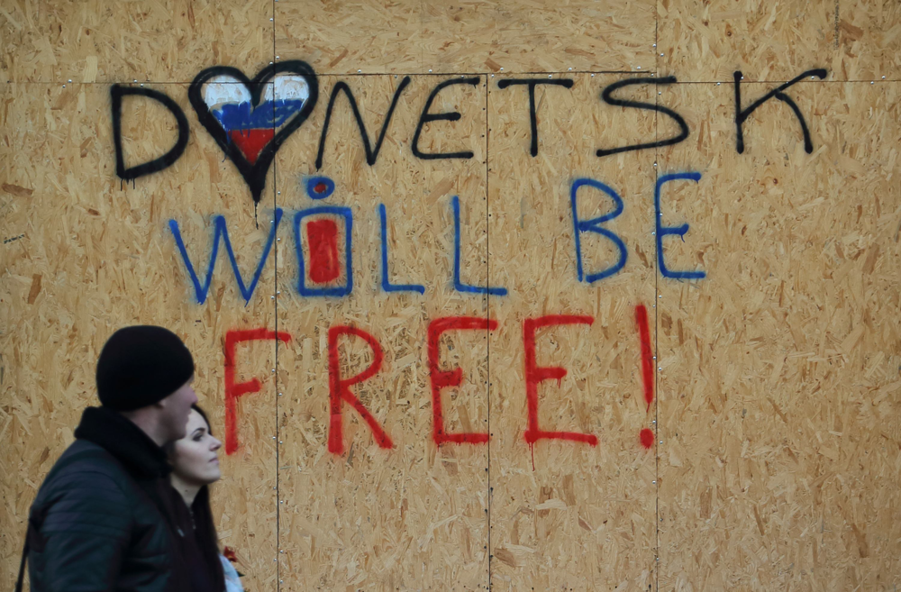 A couple passes by a sign in Donetsk downtown, the territory controlled by the self-proclaimed Donetsk People's Republic, eastern Ukraine, November 21, 2014. REUTERS/Antonio Bronic (UKRAINE  - Tags: CIVIL UNREST TRANSPORT CONFLICT)