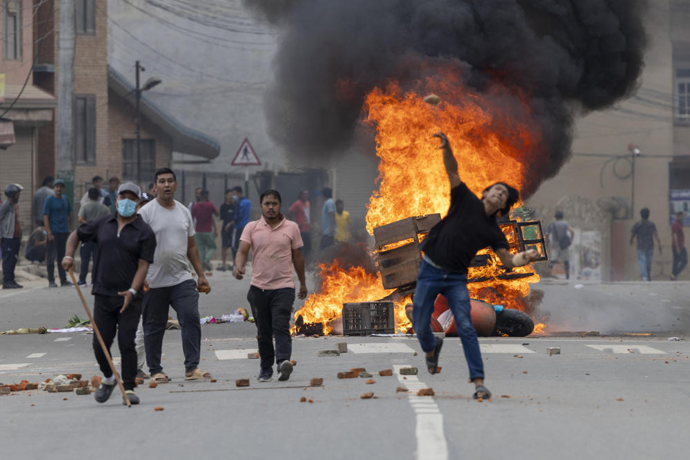epa12363982 People stand near burning barricades during protests in Kathmandu, Nepal, 09 September 2025. At least 19 people were killed and dozens injured on 08 September during demonstrations against corruption and a government social media ban. EPA/NARENDRA SHRESTHA