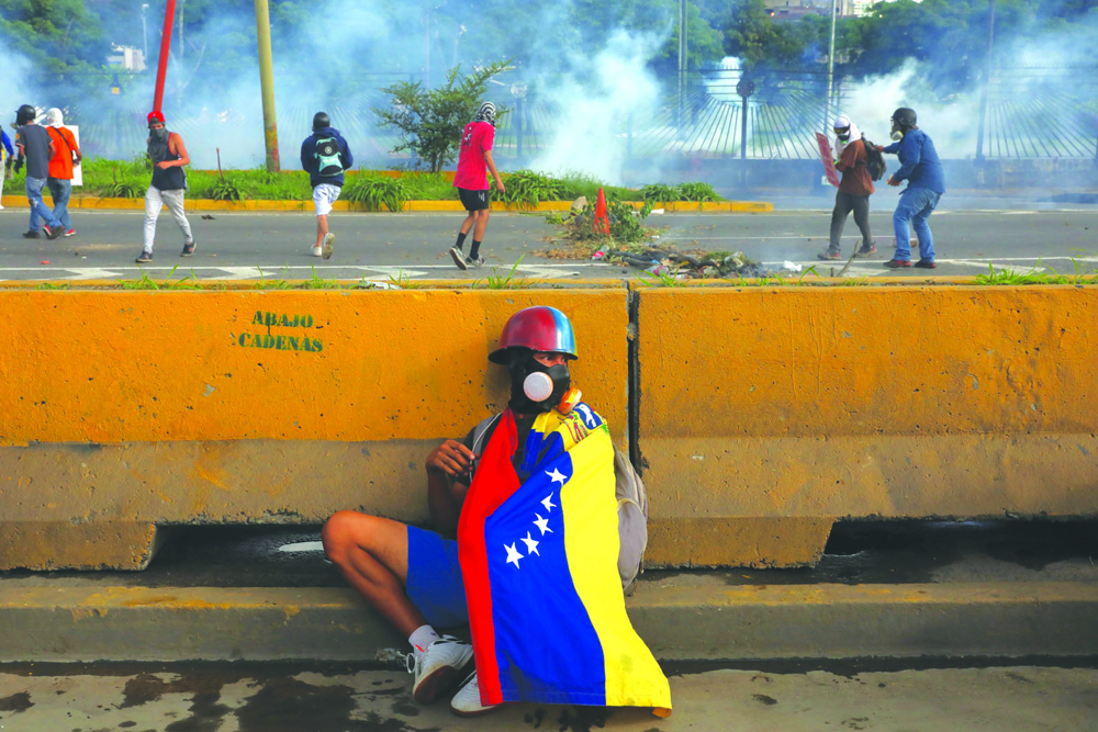 epa06044881 A protester hides behind a wall during protests in Caracas, Venezuela, 22 June 2017. The Office of the Prosecutor has confirmed 75 deaths during the wave of protests that began 01 April.  EPA/MIGUEL GUTIERREZ